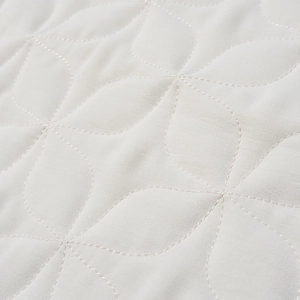 Macro detail of high-quality white quilted fabric with floral geometric stitching patterns