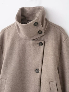Gros plan détaillé du col montant et des boutons en résine sur un manteau en laine