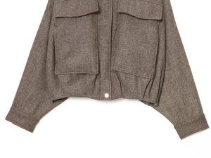 Detail of brown herringbone bomber jacket featuring two large front flap pockets