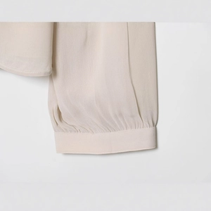Elegant off-white blouse with pleated cuffs and refined textured woven fabric details
