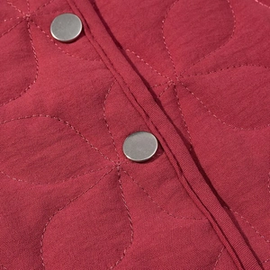 Detail of red quilted jacket with leaf pattern stitching and silver metal snap buttons