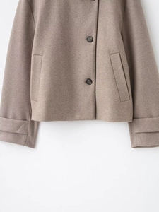 Détail des poignets larges et des boutons noirs sur une veste en laine marron clair