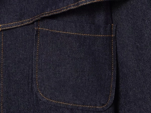 Detailed macro view of dark blue denim fabric texture and contrast stitching on pocket