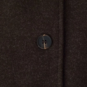 Close-up of premium dark brown cashmere wool coat featuring textured fabric and horn button