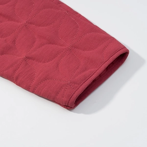 Detailed macro view of red floral quilted fabric and fine stitching on the jacket cuff
