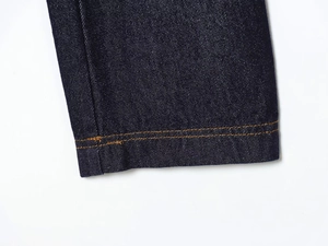 Detailed close-up of dark indigo denim fabric with orange double-needle stitching