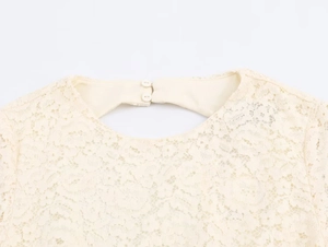 Close-up of cream lace texture with floral patterns and button back detail on dress