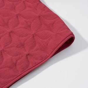 Detail of red quilted fabric with petal pattern texture and tight stitched edge