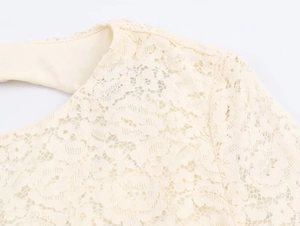 Macro shot of elegant cream lace dress detailing the intricate floral pattern and stitching
