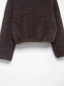 Nahaufnahme der dicken dunkelbraunen Teddy-Wollstruktur am Saum der Winterjacke