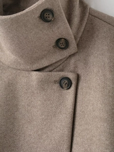 Détail du col montant et des boutons en résine sur un manteau en laine beige