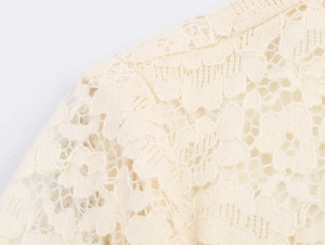 Close-up of off-white lace dress showing delicate floral hollow-out embroidery details
