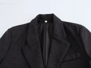 Detail of dark grey tweed blazer jacket featuring notched lapels and shoulder padding