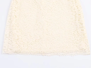 Detail of delicate off-white lace fabric with intricate floral cutout patterns and wavy edge