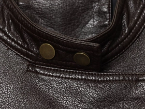 Macro shot of dark brown PU bomber jacket showing stand collar and bronze snap buttons