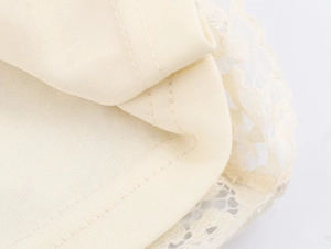 Macro shot of delicate lace trim and precision stitching on this cream mini dress