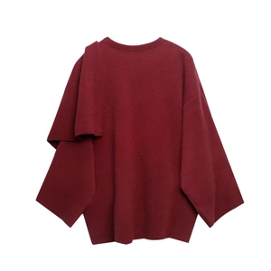 Detailansicht der dunkelroten Strickware mit einem asymmetrischen Cape-Schulter-Overlay