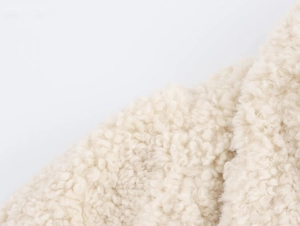 Detailed close-up of premium cream faux shearling fabric with soft curly texture