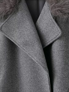 Detailed close-up of grey wool coat featuring premium faux fur collar and fabric texture