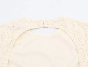 Detail of elegant back cutout and fine floral lace texture on a cream mini dress