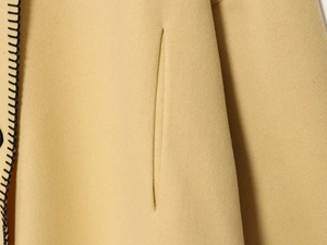 Detailaufnahme des kamelfarbenen Wollmantels mit Seitentasche und Kontrast-Handstichkanten