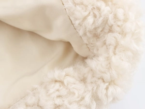 Close-up of soft beige sherpa fur texture with premium lining detail on a winter coat