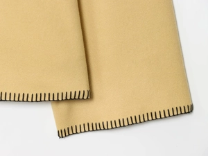 Detail von kamelbraunem Wollstoff mit schwarzer Kettelnaht für eine moderne Ästhetik