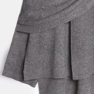 Makro-Detail des dunkelgrauen Strickgewebes mit asymmetrischen Falten und Textur