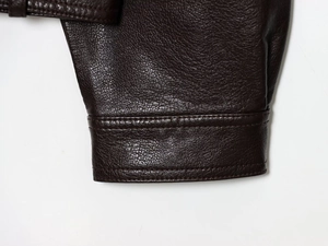 Detail of double stitching and textured brown faux leather on a bomber jacket sleeve