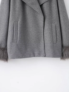 Detail of gray wool coat featuring plush faux fur cuffs and elegant vertical welt pockets