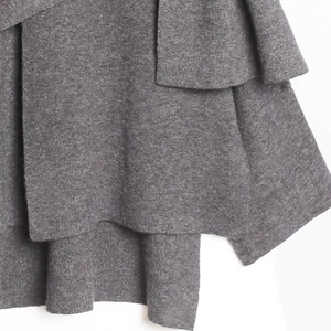 Detail der dunkelgrauen Strickstruktur mit überlappendem Rüschendesign am Saum