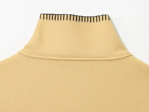 Detailed macro view of the beige wool collar with decorative black contrast stitching