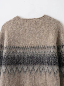 Close-up of beige knit sweater with grey geometric jacquard and fluffy mohair texture