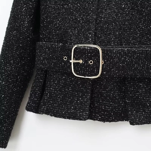 Detailed macro view of black tweed blazer texture with a golden metallic waist buckle