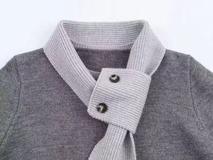 Détail de l'encolure en tricot gris avec revers superposé et boutons en marbre