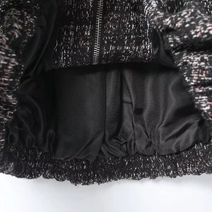 Close-up of metallic tweed fabric texture with silver threads and zipper detail