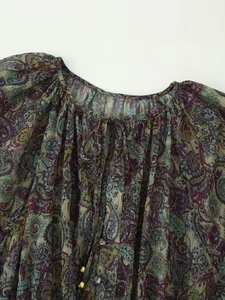 Detailed close-up of paisley chiffon dress with metallic gold thread and tie neckline