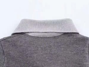 Détail d'un pull en maille grise montrant le col contrasté et le tissage fin