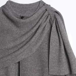 Detailansicht eines grauen Strickponchos mit weicher Wollstruktur und elegantem Knopfverschluss