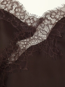 Close-up of chocolate brown satin fabric with delicate eyelash lace trim detailing