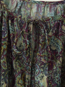 Detail of metallic thread Paisley print and ruffled tie-neck on a mini dress