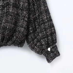 Close-up of black and silver tweed jacket sleeves with metallic thread and silver buttons
