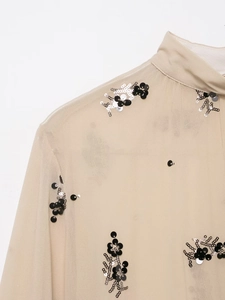 Detail of sheer beige shirt with intricate black and silver sequin flower embroidery