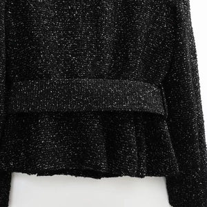 Close-up of black tweed fabric texture with subtle sparkles and refined waist stitching