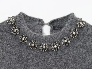 Close-up of grey knit sweater featuring intricate floral rhinestone beadwork at neckline