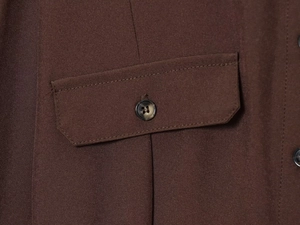 Detail of dark brown shirt dress showing pocket flap and tortoise shell button textures