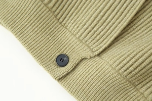 Detail of grass green ribbed knit sweater showing fine texture and black round button