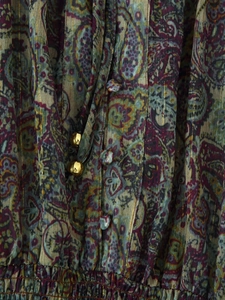 Macro detail of paisley printed fabric with metallic gold thread and elastic waist design