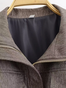 Details des Fischgrätmusters mit goldenem Reißverschluss an der braunen Bomberjacke