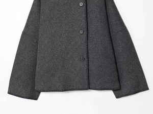 Detail of grey knitted cardigan with contrast black edge stitching and round buttons